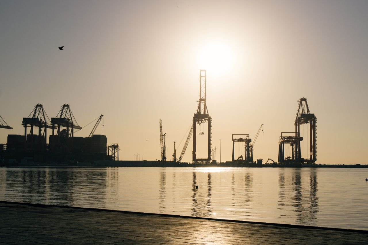 Shipyard cranes silhouetted at sunrise, representing US shipbuilding capacity under the SHIPS for America Act